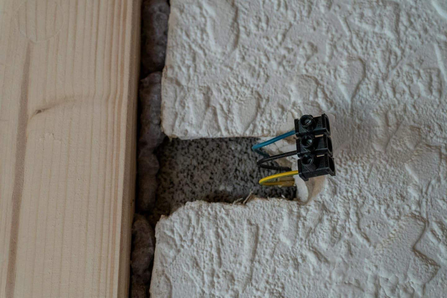 Elektriker installiert blaue und gelbe Kabel in einer Wand.